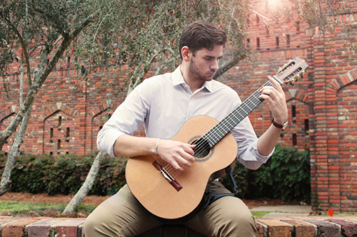 MSU student Eli Denson strums a guitar while sitting near the Chapel of Memories