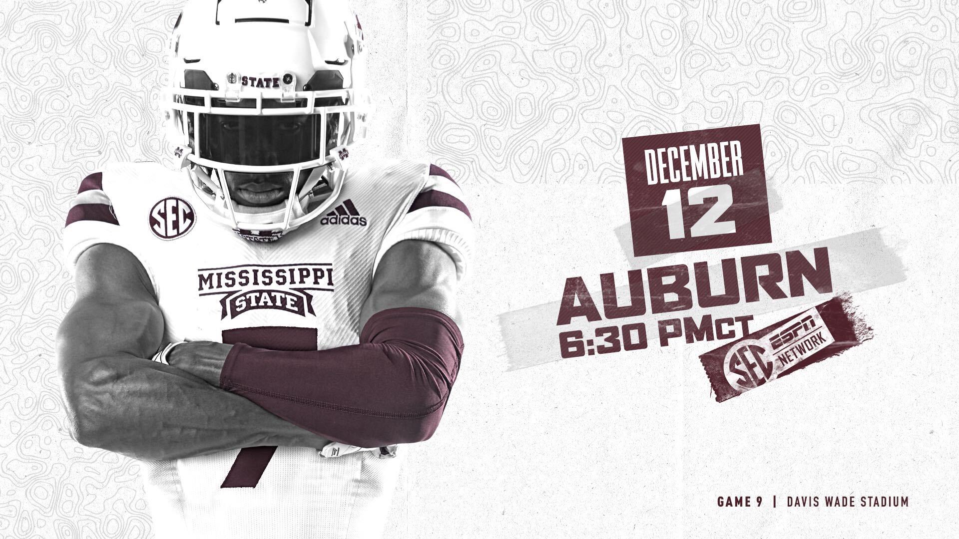 A Mississippi State football player in a white uniform stares at the camera while crossing his arms over his chest.