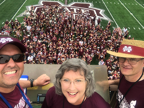 From left, MSU Associate Director of Bands Craig Aarhus, Director of Bands Elva Kaye Lance and Associate Director of Bands Cliff Taylor smile for a group photo with the 414-member Famous Maroon Band during a recent rehearsal on the band’s new synthetic practice field. (Photo submitted/Craig Aarhus)