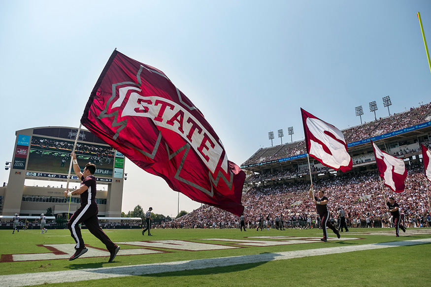 Cheerleaders run on the field during a 2019 MSU football game.