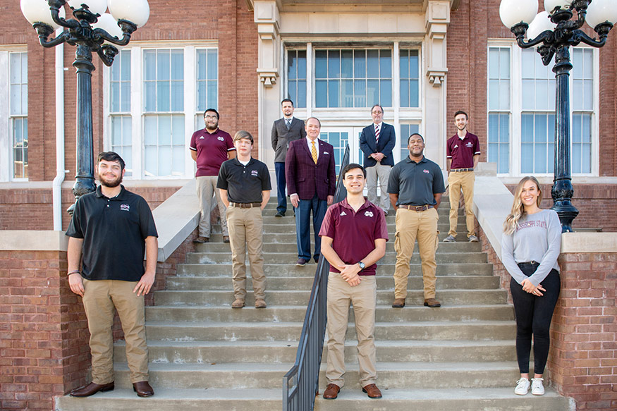 A group of forestry majors are pictured, sociaally distanced, on the steps of Lee Hall with MSU President Mark Keenum and their forestry advisor and department head