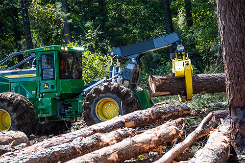 Heavy equipment moving logs during a forestry show demonstration