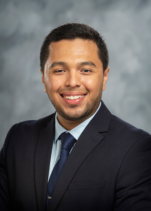 Portrait of Eduardo S. Garay wearing a suit and tie in front of a gray background