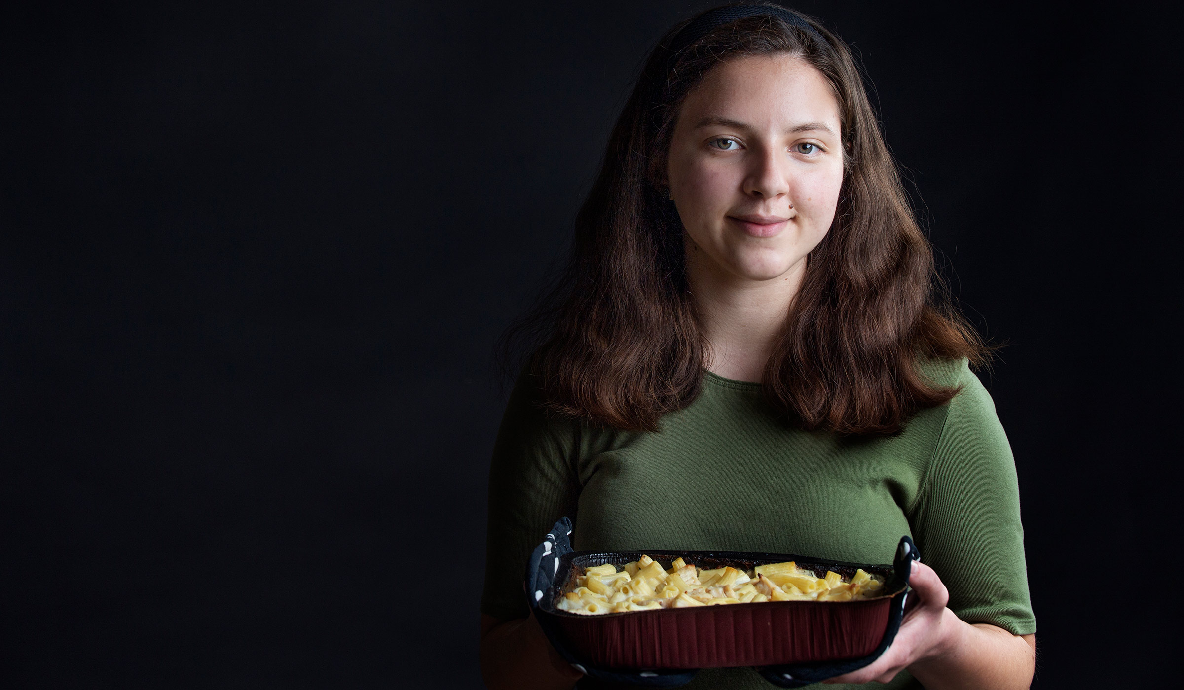 Yuliya Gluhova, pictured holding a casserole in dark lighting.