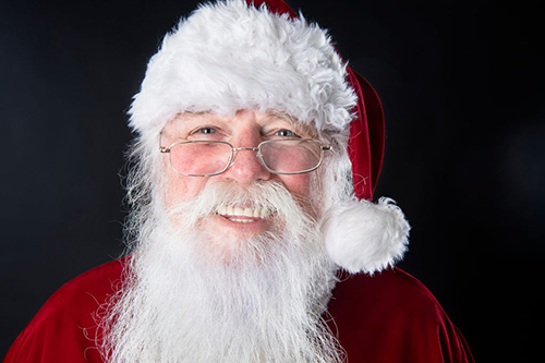 Retired MSU College of Business instructor Mike Goree smiles for the camera while wearing his bright red Santa suit.