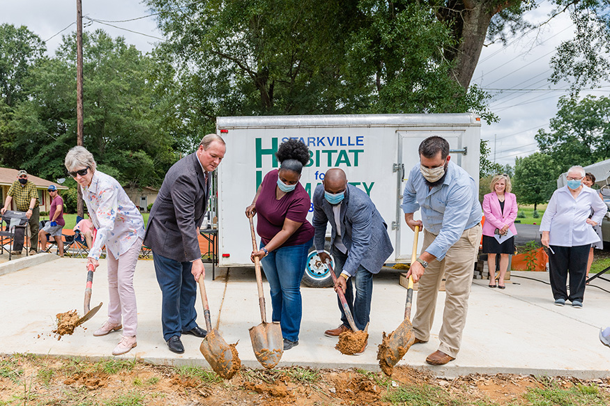 Starkville Mayor Lynn Spruill, MSU President Mark E. Keenum, homeowner Keva Robertson, Rev. Abdural Lee of Sand Creek Chapel Church, and Starkville Area Habitat for Humanity President Jesse Morrison use shovels to scoop clay at the site of Habitat's newest Maroon Edition home in Starkville.