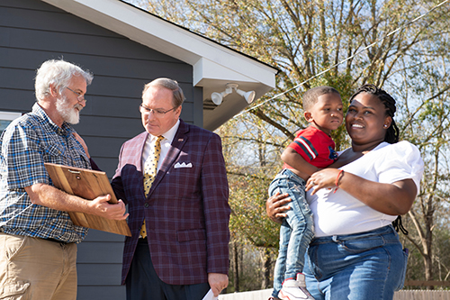 Starkville Area Habitat for Humanity Construction Manager John Breazeale, MSU President Mark E. Keenum, Starkville homeowner Keva Robertson holding her son Laquante in front of Robertson's new home