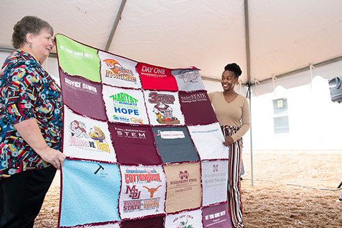 Dot Livingston presents a t-shirt quilt, representing the Mississippi State students and student organizations that worked on the 10th Maroon Edition Habitat for Humanity home, to new homeowner Lou’Quan Lucious. (Photo by Megan Bean)