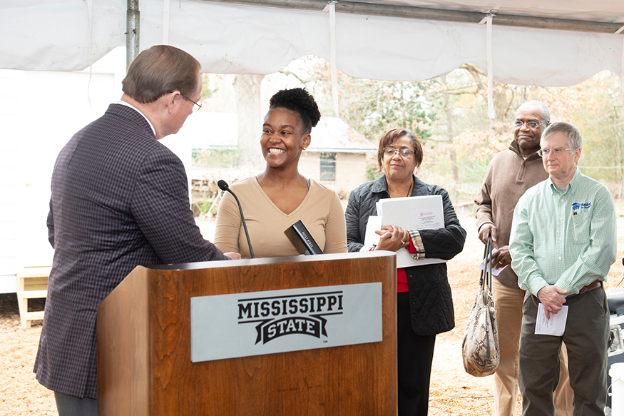 MSU President Mark E. Keenum presents a family Bible to Lou’Quan Lucious, who will move into the 10th Maroon Edition Habitat for Humanity home in time for the Christmas holidays. (Photo by Megan Bean) 