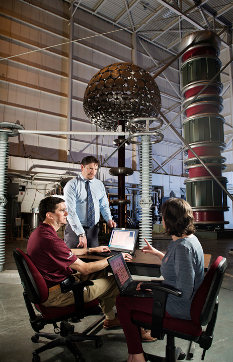 Mississippi State University Center for Advanced Vehicular Systems researchers Greg Henley, Mike Mazzola (standing) and Angela Card collaborate in MSU’s Paul B. Jacob High Voltage Laboratory. The engineers are working in collaboration with Entergy to develop software that will improve the reliability of U.S. electrical systems. (Photo by Megan Bean)