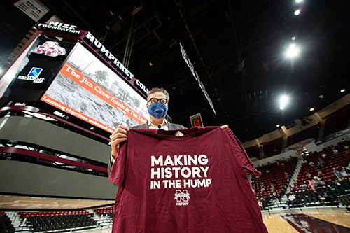 Jim Giesen holds up a "Making History in the Hump" T-shirt while teaching in Humphrey Coliseum.