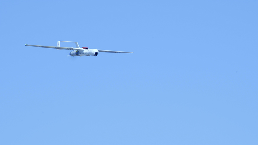 An UAS flies across a clear sky
