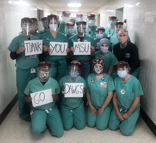 Rush Health Systems nurses hold up signs that read "Thank You MSU Go Dawgs" while wearing face shields made by MSU faculty and staff.
