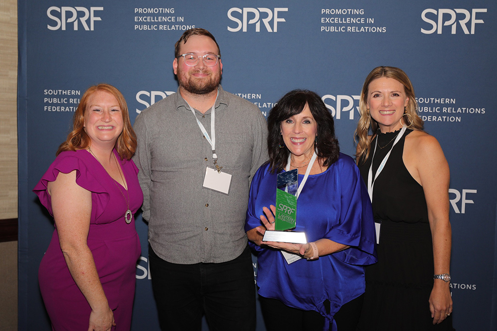 The College of Arts and Sciences communication team is presented with a trophy