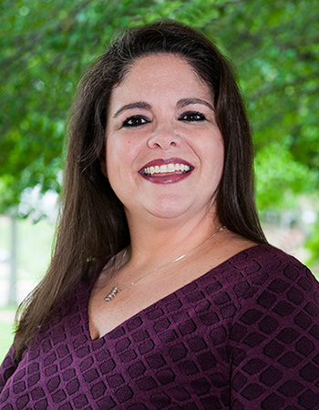 Portrait of Kay Brocato, she is standing outside and is wearing a purple top