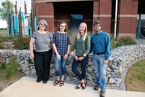 Raingarden project leaders include (l-r) Suzanne Powney, assistant professor in art and graphic design; Lauryn Rody, senior art major with a graphic design concentration; Caitlin Buckner, landscape architecture senior; and Cory Gallo, associate professor in landscape architecture. Powney and Gallo led the design/build class last spring; Rody and Buckner attended the class as juniors. The class put the final elements in place for the raingarden. (Photo by Megan Bean)