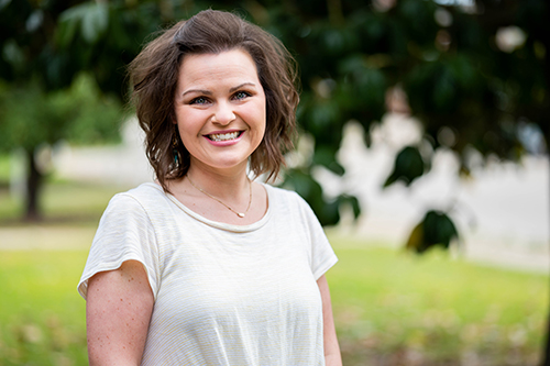 Mississippi Teacher of the Year Leslie Tally, a two-time graduate of MSU's College of Education, smiles while standing near trees in a grassy field.