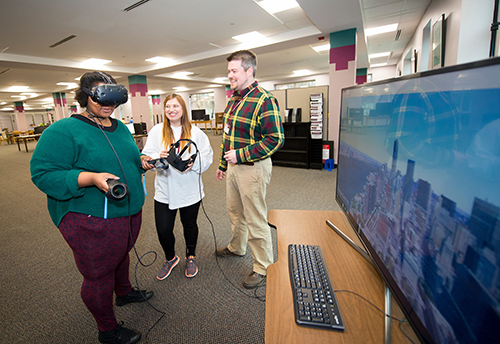 Ebony Preston, a junior elementary education major from Yazoo City, explores New York City using virtual reality equipment in MSU Libraries’ new CAVS Mixed Reality Lab as Katelyn Cheatham, a graduate student in English from Philadelphia, and MSU Libraries Instructional Technology Specialist Thomas La Foe look on. (Photo by Russ Houston)