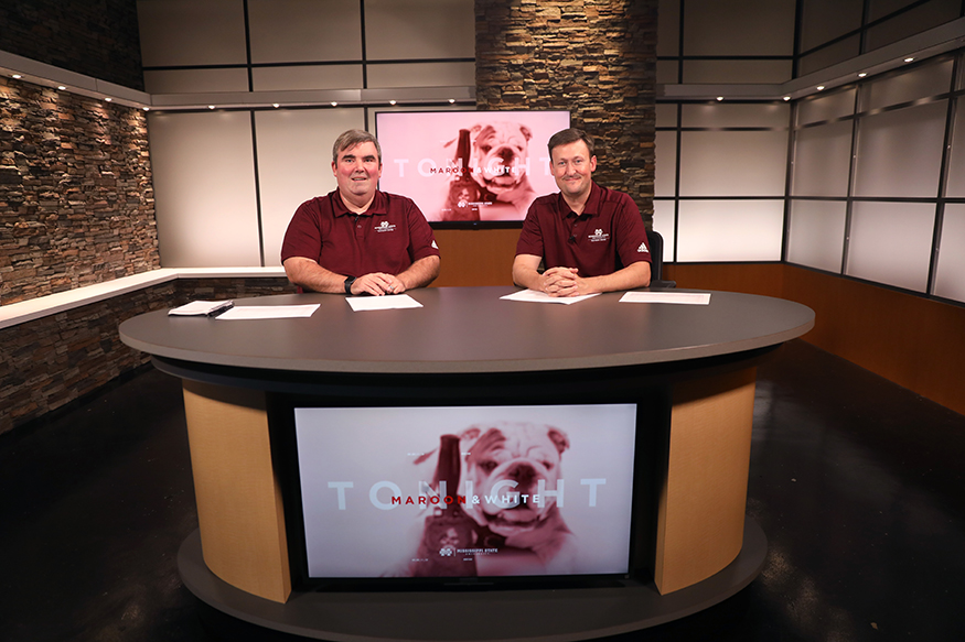 Neil Price and Anthony Craven sit at a large desk in the University Television Center studio on the set of “Maroon and White Tonight.”