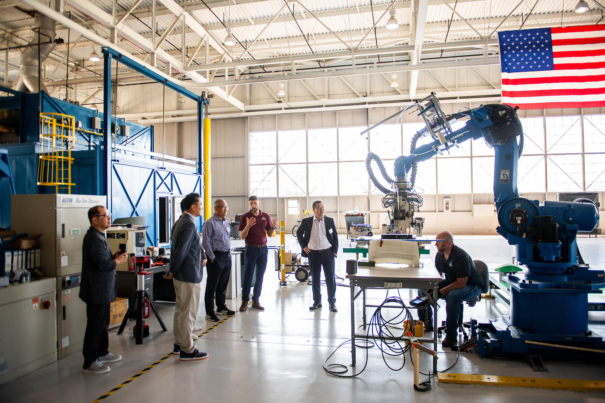 Visitors tour the Advanced Composites Institute, which includes large equipment in a hangar setting