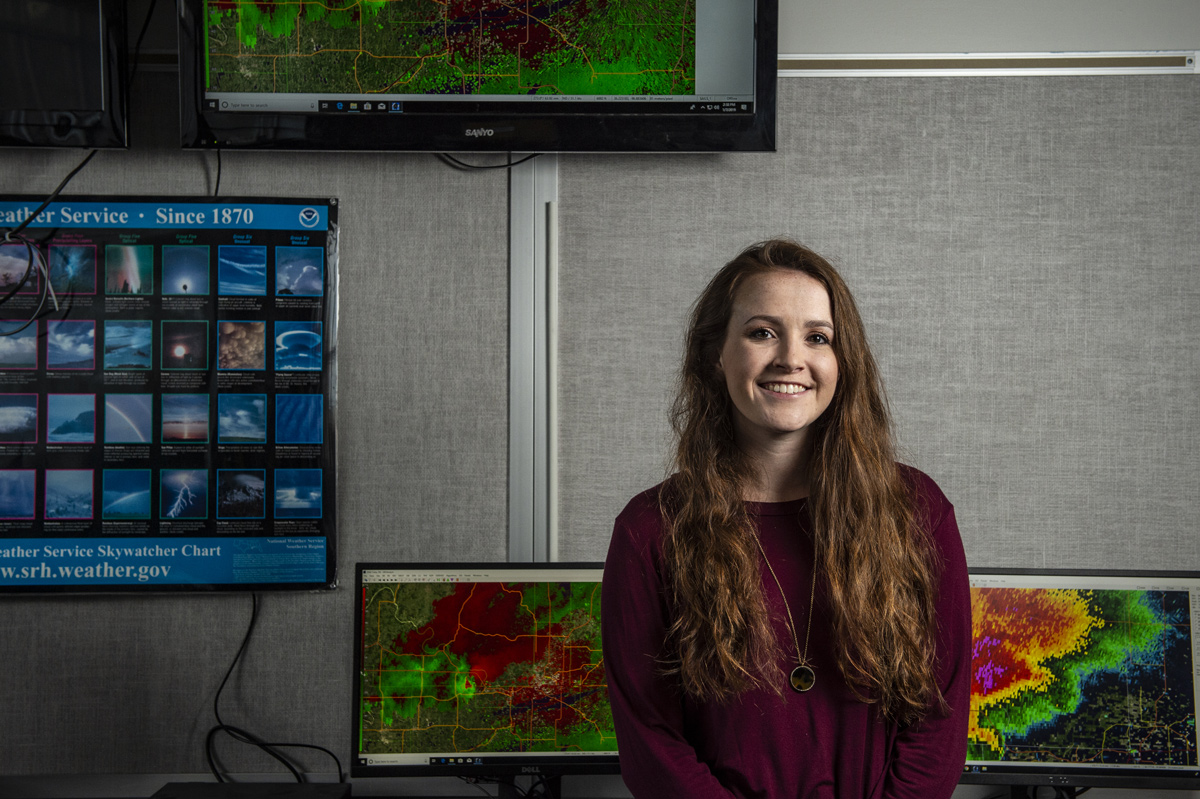 Caroline MacDonald, pictured in front of computers with severe weather warnings.
