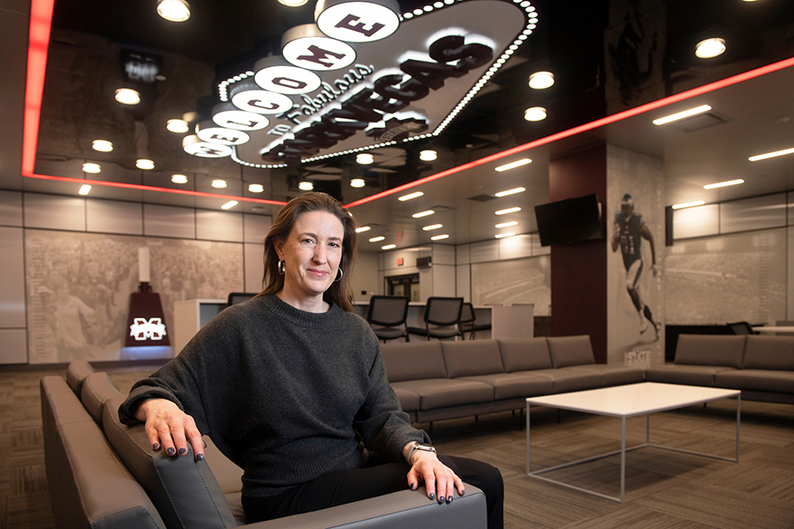 Environmental portrait of Mary McLendon seated in football recruiting lounge at Davis Wade Stadium