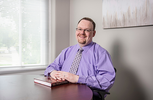 Michael Nadorff smiles for the camera while seated at a table in his George Hall office.