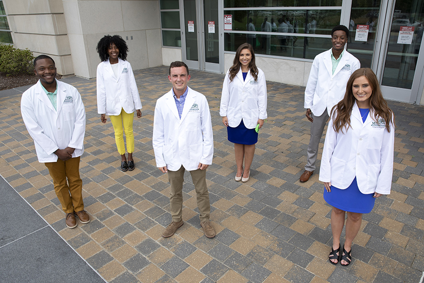 MSU students Tyus Wilson, Caleb McCreary, Makenzie Downs, Kayla Williams, Layne Boykin and Donovan Gordon pictured outside in white lab coats