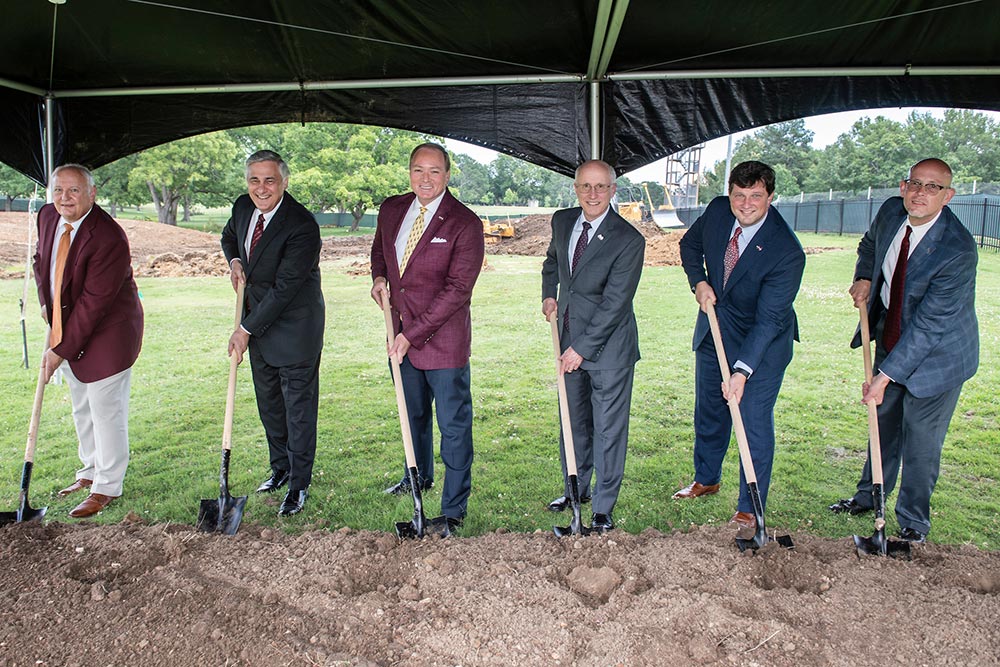 Six men hold shovels during a groundbreaking ceremony.