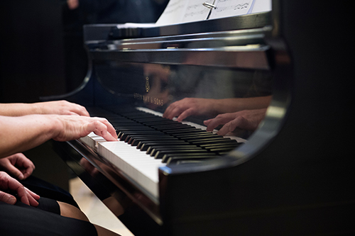 Close-up of hands of two people playing on a Steinway & Sons piano