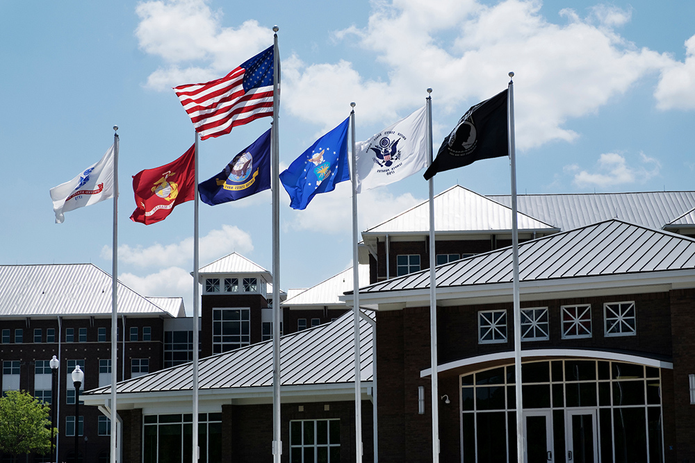 Flags representing military service branches fly in front of MSU's Nusz Hall