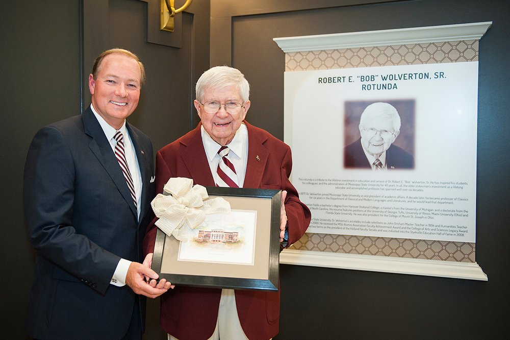 Mark Keenum presents Robert Wolverton with a painting next to a marker for the rotunda named in Wolverton's honor.
