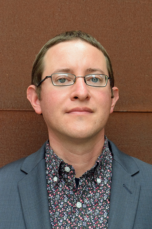 Portrait of Owen James Hyman wearing glasses and a sport coat.