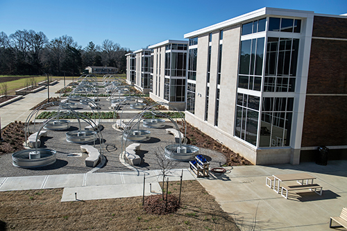 A large building on the right has raised beds and other gardening infrastructure prepared outdoors.