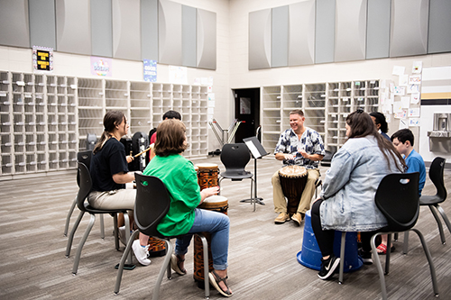A professor leads a drum circle during a music lesson