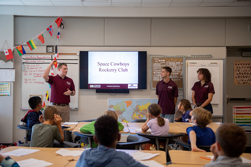 Students present in front of a screen that says "Space Cowboys Rocketry Club"