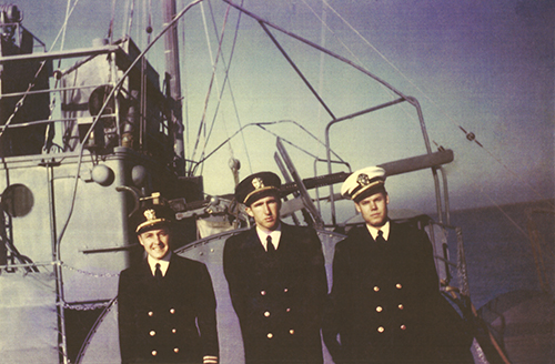 Officers stand aboard a ship during WWII