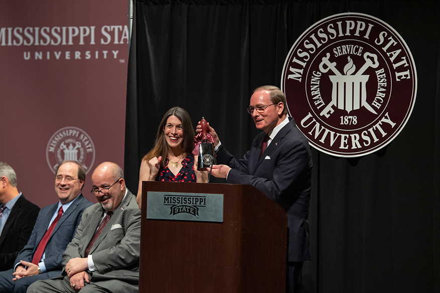 Mark Keenum presents a cowbell to Catherine Pierce