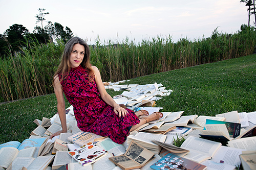 Portrait of Catherine Pierce sitting on a pathway of books outside