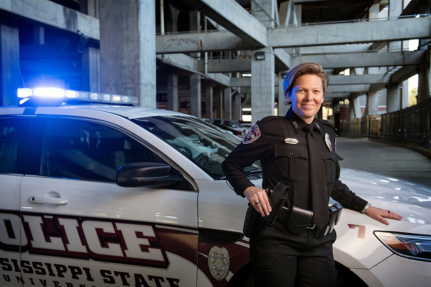 Corporal Stephanie Perkins stands by an MSU Police car with a blue light shining