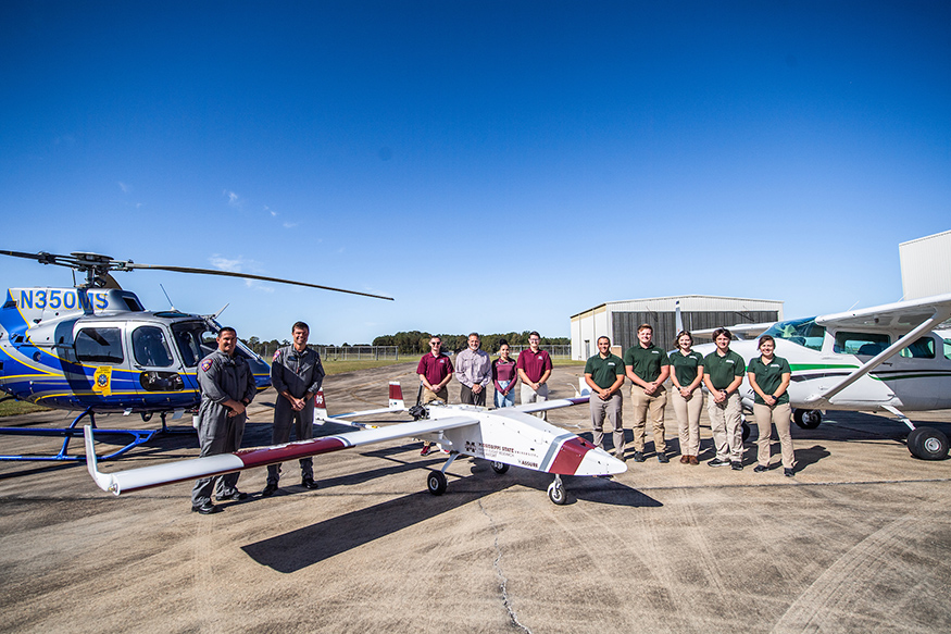 Pilots from MSU, MHP and DSU stand in front a helicopter, conventional aircraft and uncrewed aircraft system.