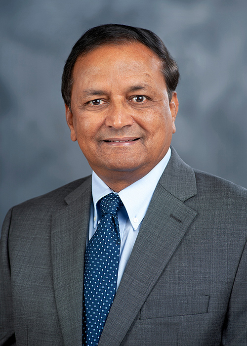 Studio portrait of Raja Reddy wearing a coat and tie