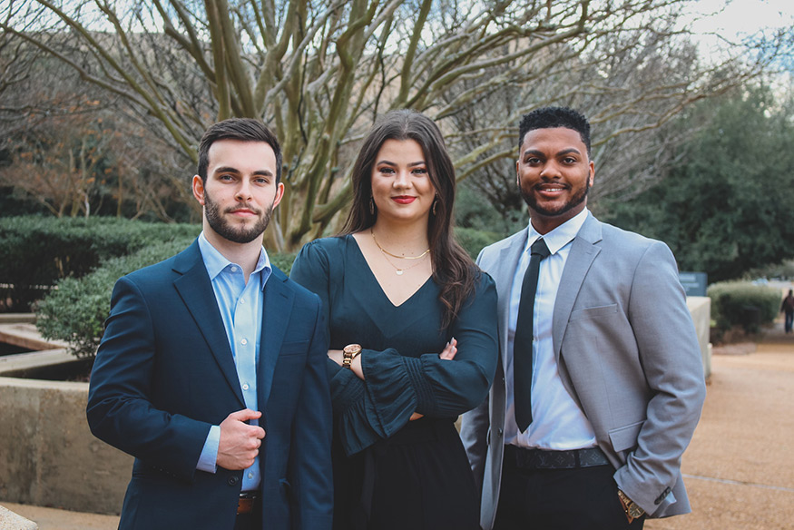 A photo of three business owners -- two men and one woman -- stand outside MSU's Hunter Henry Center.