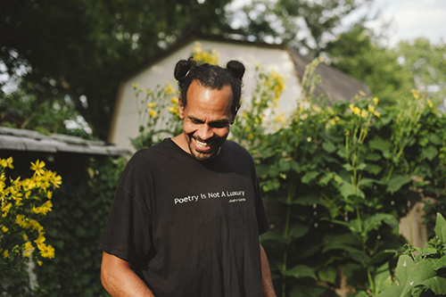 Portrait of Ross Gay outdoors with flowers in the background