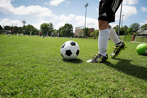 A close up shot of a child's legs kicking a soccer ball