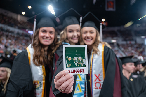 Three Mississippi State graduates show a photograph of themselves taken at one of Friday's commencement ceremonies at Humphrey Coliseum. 