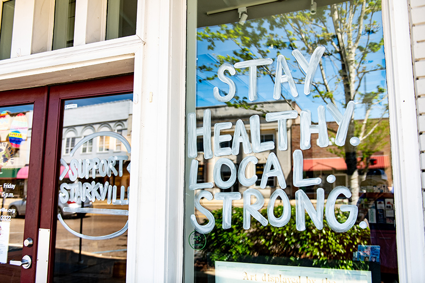 An encouraging reminder to “stay healthy, local and strong” is pictured on the Greater Starkville Development Partnership’s front window in downtown Starkville.