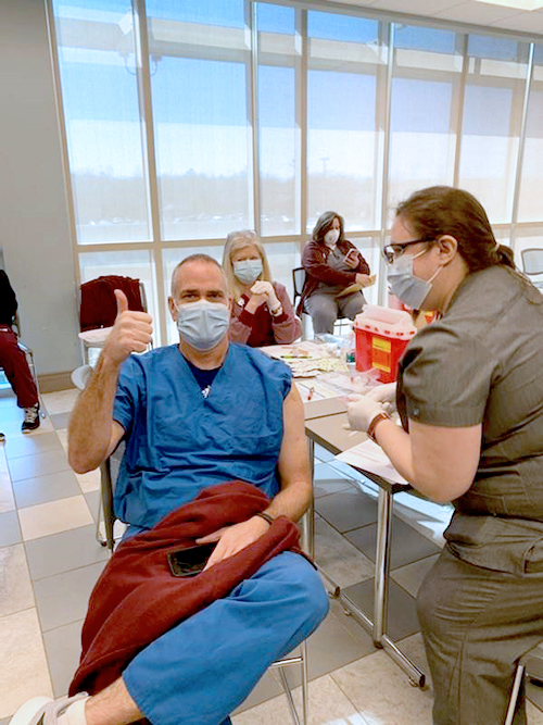 Dr. Cliff Story gives a thumbs up as he receives a vaccination shot