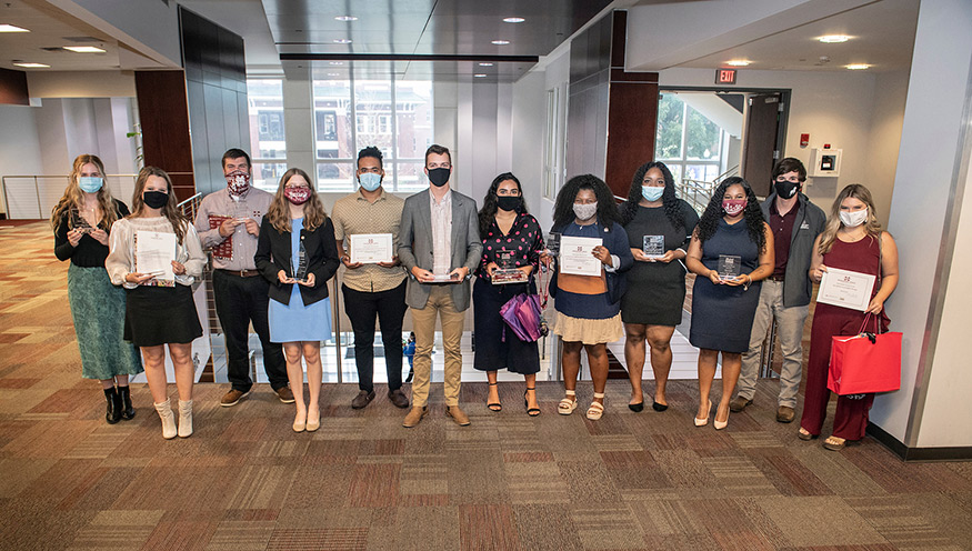 A dozen students wearing face masks pose with their awards.
