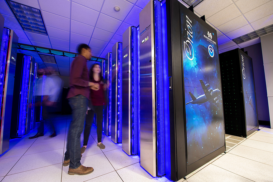 Employees walk around MSU's Orion supercomputer.